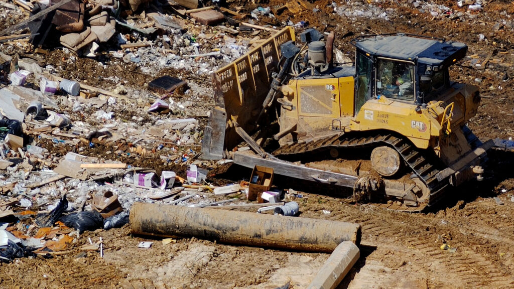 Close-up on bulldozer as it moves garbage at a landfill